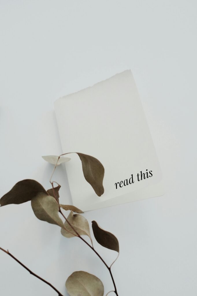 Minimalist photo of paper with 'read this' text and eucalyptus leaves on white background.